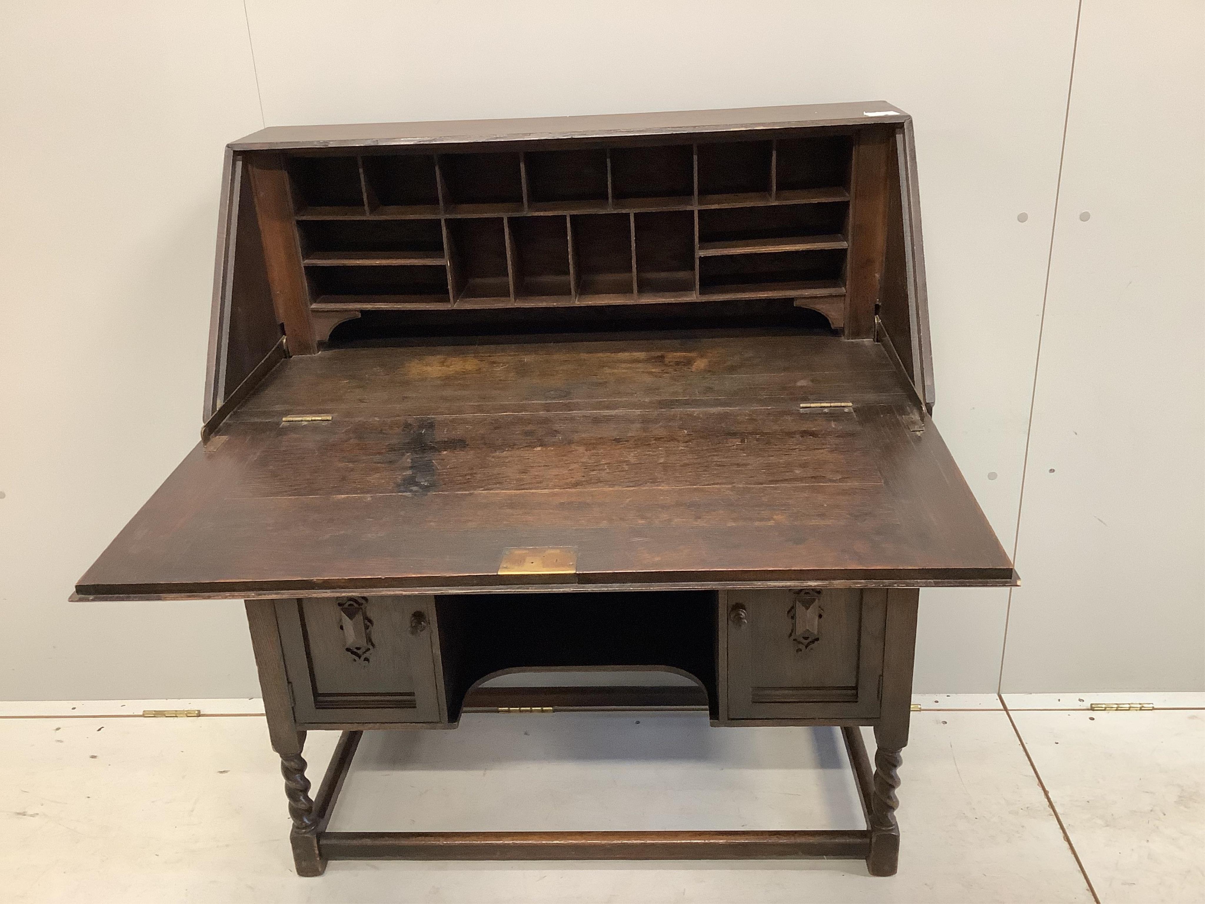 A dark oak Tudor style bureau with a decorative carved front, single drawer above cupboard doors, width 91cm, depth 42cm, height 109cm. Condition - fair